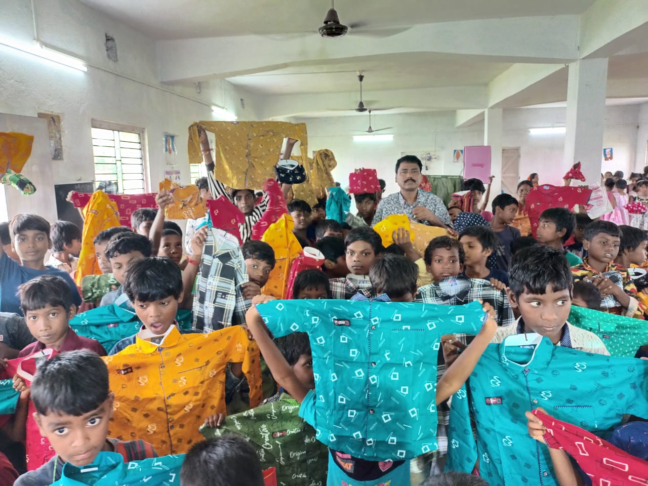 Children holding up new clothes they received at a distribution